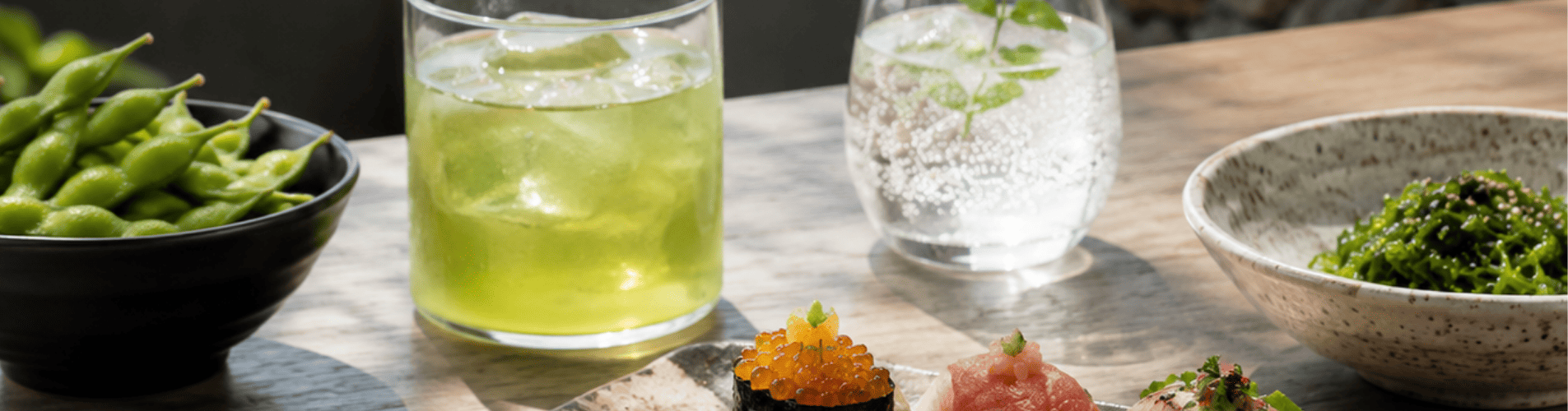 Imagen de sushi fresco acompañado de té verde frío, agua con gas y bocados ligeros, pensada para mostrar maridajes suaves y refrescantes sin alcohol.